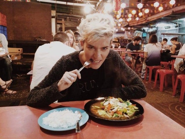 Autorin Mia Bühler sitzt am Tisch vor einem Teller chinesischen Essens und beißt in die Gabel