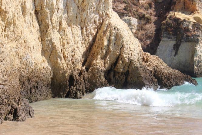 Wellen schlagen gegen die Felsen an der Praia dos Três Irmãos