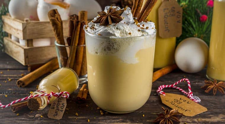 Blick auf ein Glas mit Eggnog, im Hintergrund Zimtstangen und Eier, New York, USA