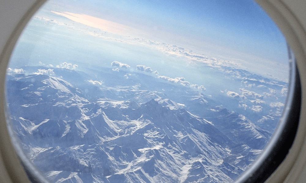 Bild aus dem Flugzeugfenster mit Blick auf die Alpen.