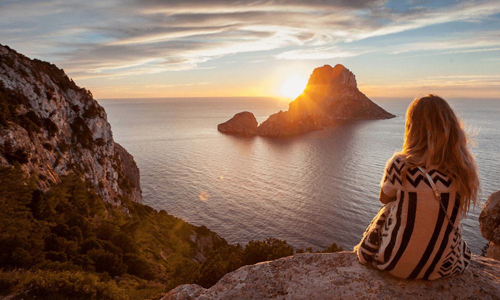 Frau schaut sich den Sonnenuntergang auf Ibiza an.