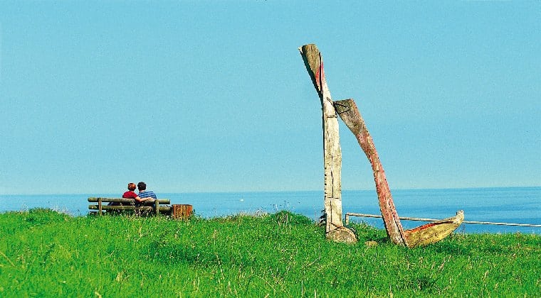 Ein Paar sitzend auf einer Bank mit Blick aufs Meer