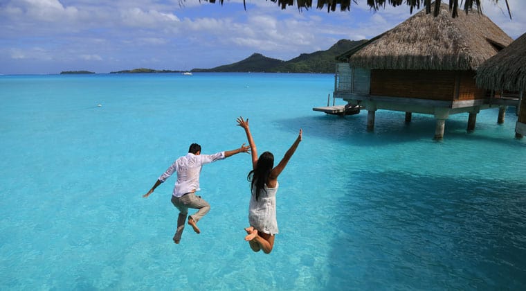 Pärchen springt auf Bora Bora vom Wasserbungalow ins Wasser