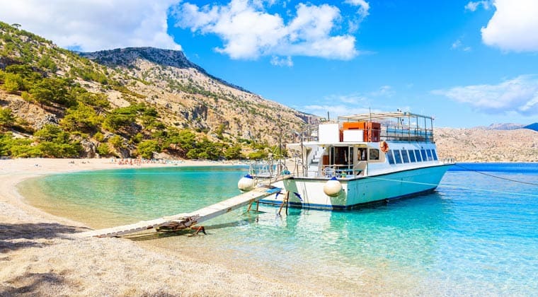 Kleine Fähre ankert an einem Strand der Insel Korfu
