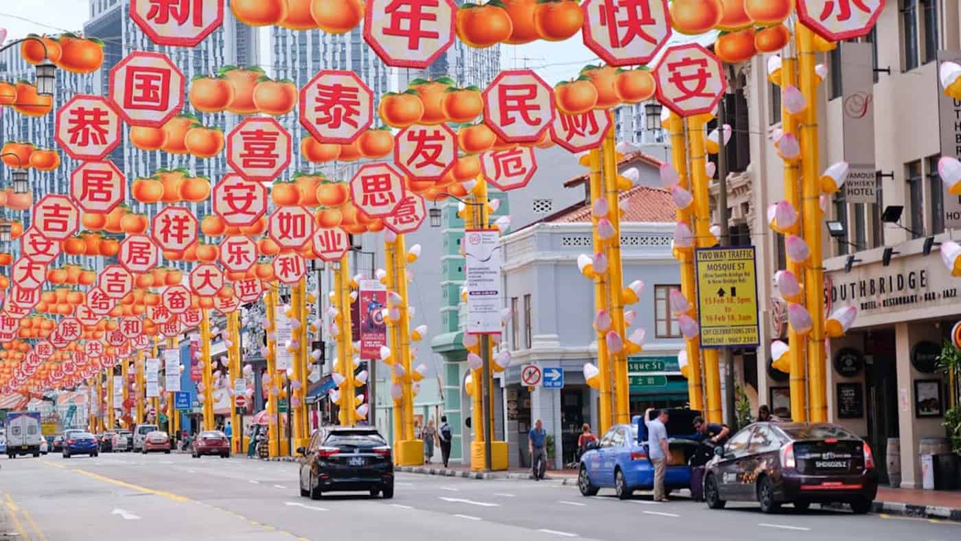 Blick auf eine Strasse in China Town mit Autos und orange-gelber Deko über der Strasse, Singapur, Südostasien
