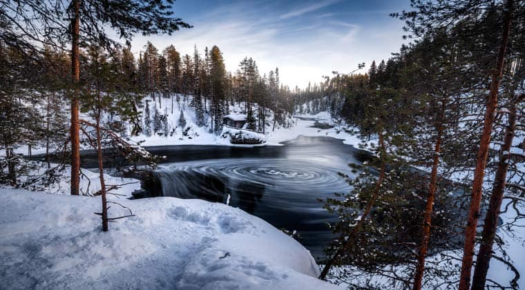 Traumlandschaft im Winter in Finnland - verschneite Waldlandschaft mit See.