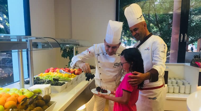 Zwei Koeche stehen mit einem Kind am Buffet des Restaurants