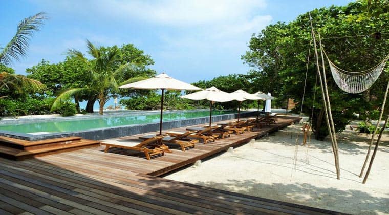 Malediven The Barefoot Hotel Pool mit Liegen und Sonnenschirmen