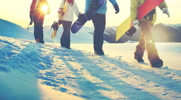 Menschen mit Snowboards stapfen im Schnee