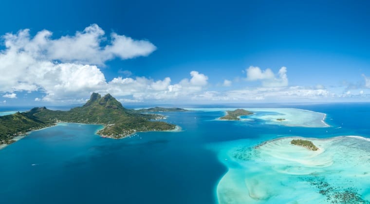 Blick aus dem Helikopter auf die Inselkette Französisch-Polynesien und das türkisblaue Wasser des Südpazifiks