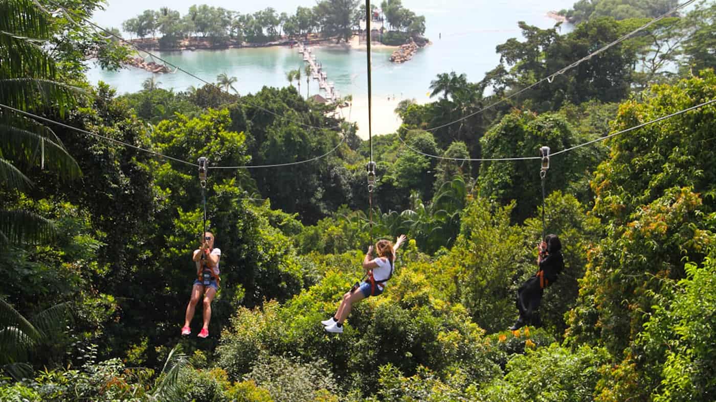 Blick auf zwei menschen beim Ziplining über Sentosa Island, Singapur, Südostasien