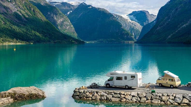 Ein Wohnmobil und ein Campervan an einem See in Norwegen umgeben von unglaublich schönen Bergen und Gletschern.