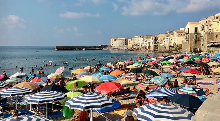 Der Strand von Cefalù in Sizilien, Italien, übersät mit unzähligen bunten Sonnenschirmen.