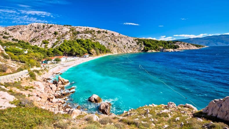 Blick auf den hellen Strand und das türkisfarbene Wasser des Bunculuka Strandes, Insel Krk, Kroatien