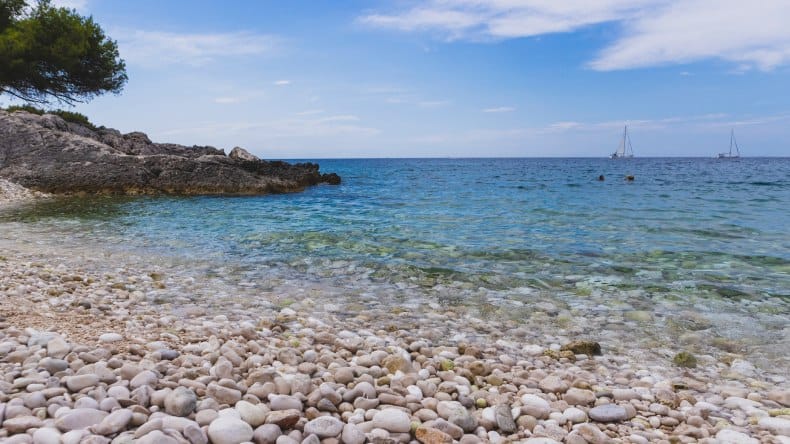 Blick auf die von Felsen und Kiefern eingerahmte Kieselbucht Mekićevica, Insel Hvar, Kroatien
