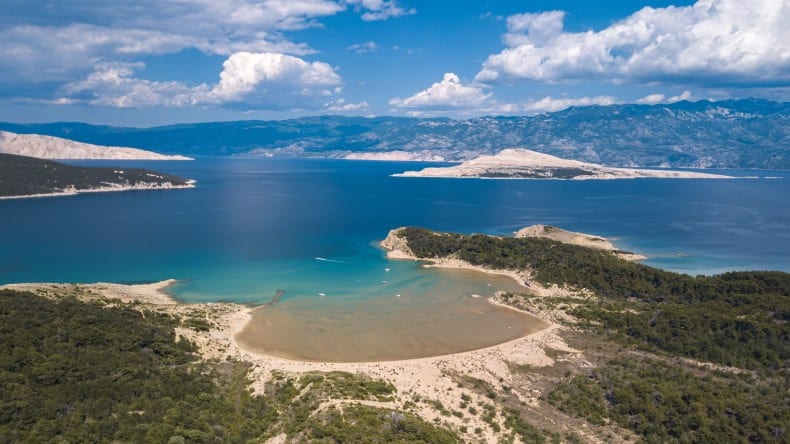 Blick von oben auf den Saharastrand mit goldgelbem Sand und blauem Wasser, Insel Rab, Kroatien