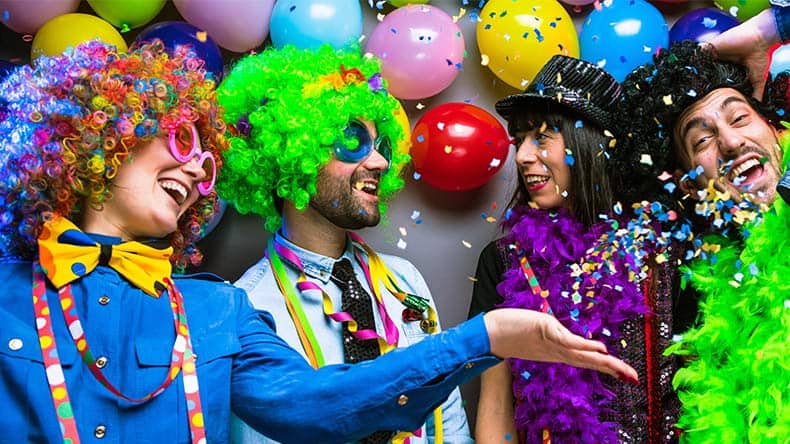 Lachende Freunde in bunten Kostümen feiern Karneval