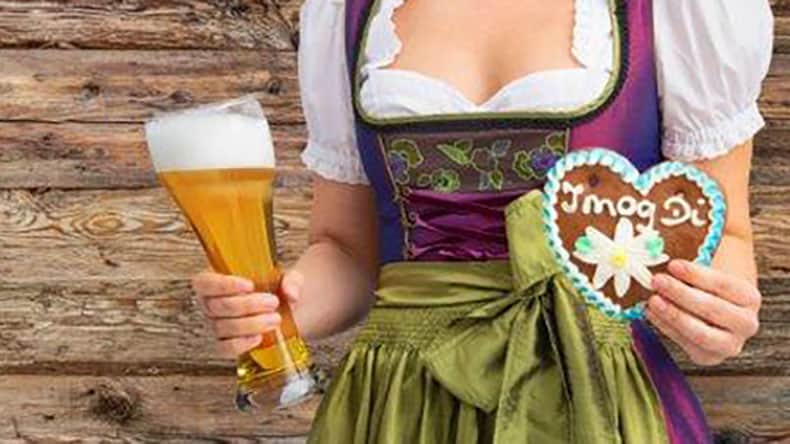 Frau im Dirndl mit Bierglas und Lebkuchenherz in der Hand