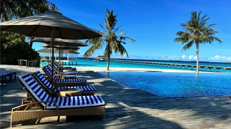 Liegen und Sonnenschirme am Infinitypool vom ROBINSON NOONU Club auf den Malediven.