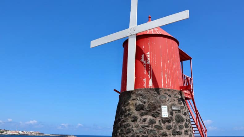 Eine eine kleine rote Windmühle im Hafen auf der Insel Pico.