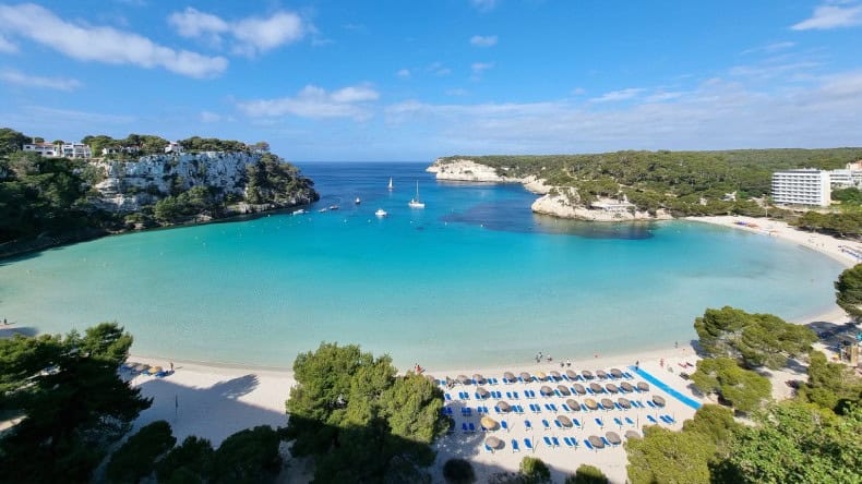 Blick auf die Bucht Cala Galdana, heller Sandstrand, grüne Felsen, türkisfarbenes Meer, Menorca, Balearen