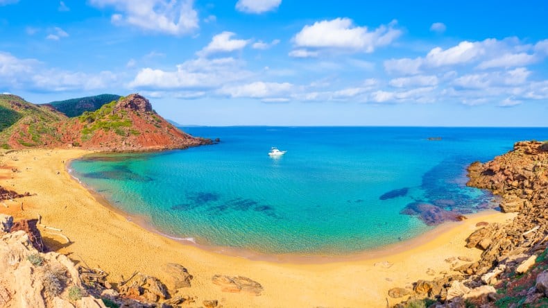 Blick auf die Bucht Cala Pilar mit ihrem goldgelben Sand, Felsen und türkisfarbenem Meer, Menorca, Balearen