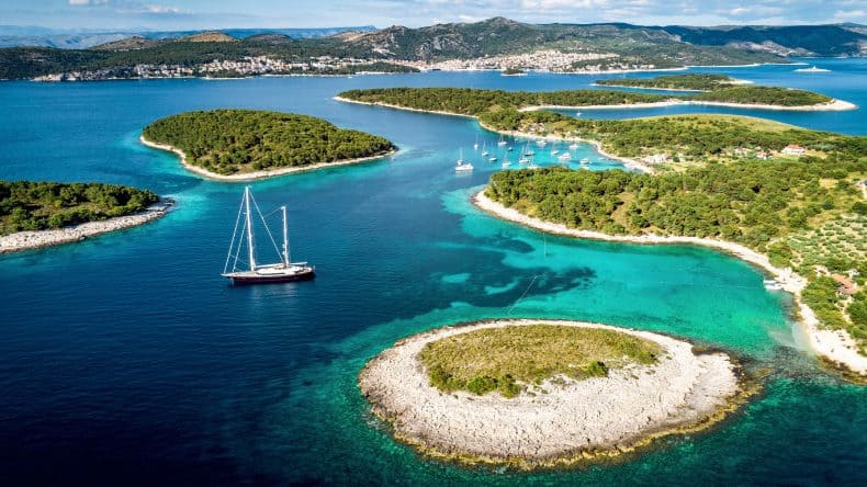 Blick auf grün bewachsene Inseln, türkisblaues Meer und ein Schiff, Hvar, Kroatien