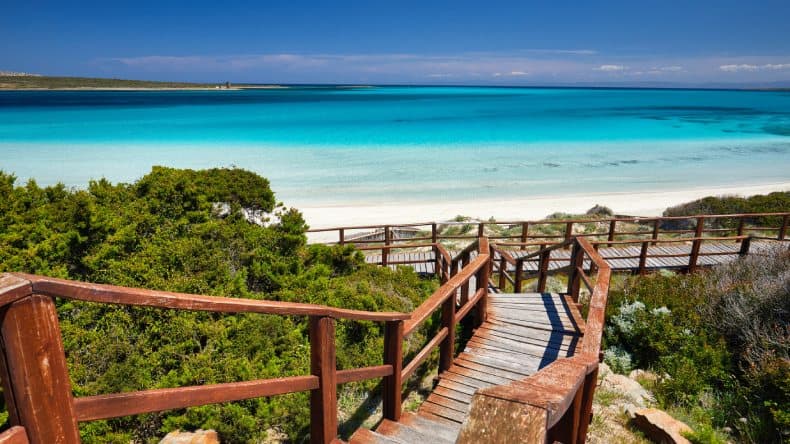 Blick auf den La Pelosa Strand, eine Holztreppe, weißen Sand und türkisfarbenes Wasser, Sardinien, Italien
