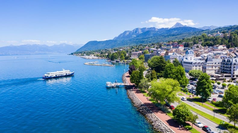 Blick auf den Badeort Évian-les-Bains am Südufer des Genfer Sees in Frankreich, Schiff, blaues Wasser, Stadt, grüne, hügelige Umgebung