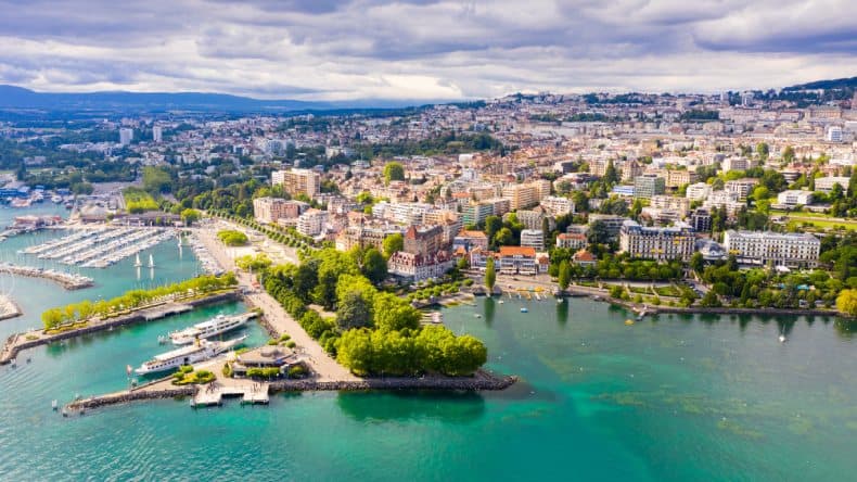 Blick von oben auf die Stadt Lausanne am Genfer See, türkis-blaues Wasser, Stadt, Häuser, grüne Bäume, Schweiz