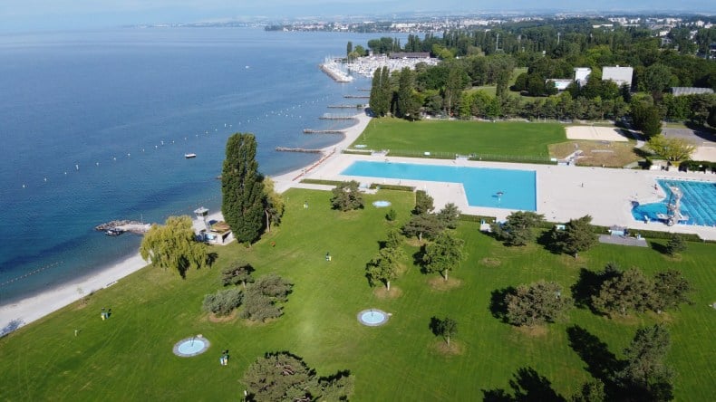 Blick von oben auf das Strandbad Bellerive-Plage, zwei Schwimmbecken, grüne Wiesen, Bäume, See, blaues Wasser, Lausanne, Schweiz
