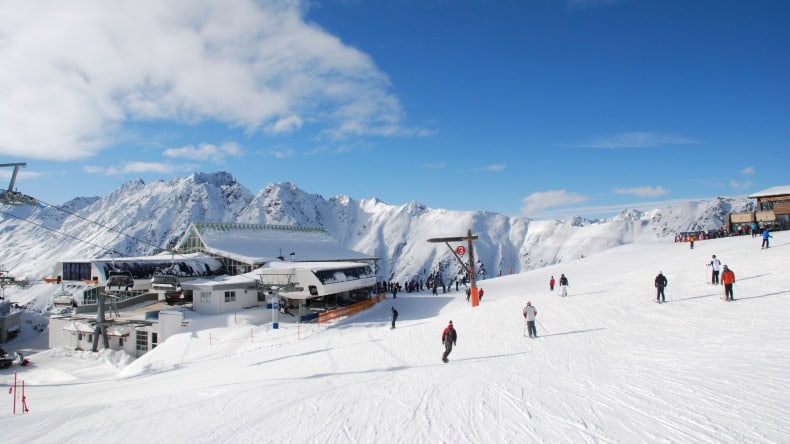 Blick auf eine Skistation in Ischgl, Schnee, berge, blauer Himmel mit weißen Wolken, Skifahrer, Österreich