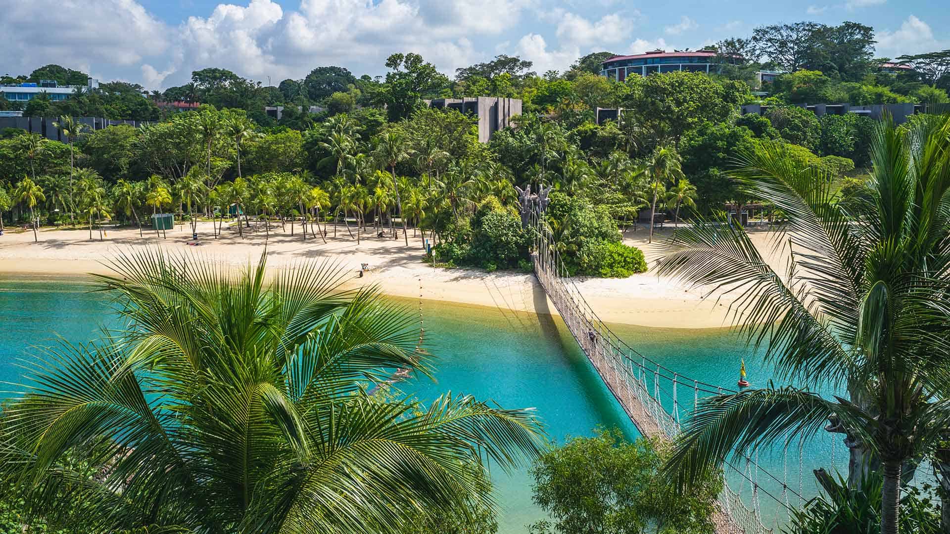Blick auf Sentosa Island mit Brücke, Strand und Palmen, Singapur
