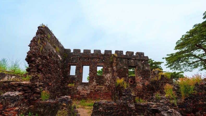 Blick auf die Steinruinen des Fort St. James inmitten grüner Vegetation auf der Insel Kunta Kinteh, Gambia, Westafrika