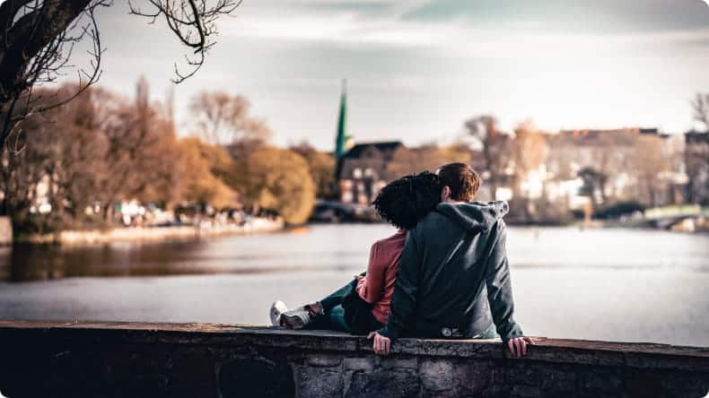 Junges Paar sitzt am Flussufer