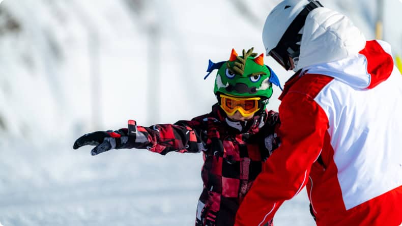 Ein Junge lernt Snowboarden mit einem Skilehrer