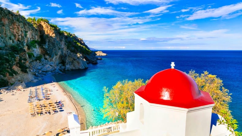 Karpathos, Griechenland, Strand Kyra Panagia. Kirche mit roter Kuppel und Blick aufs Meer und Strand.