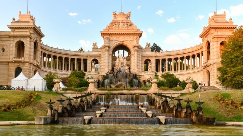 Blick auf Palais Longchamp mit Springbrunnen und Wasser im Vordergrund
