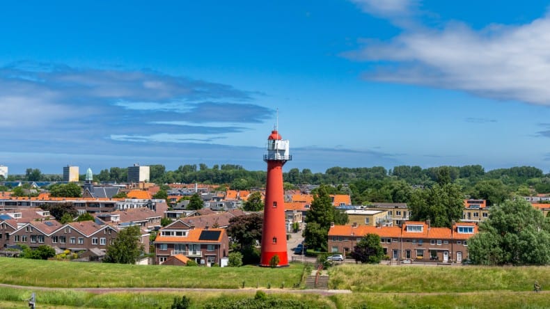 Blick auf Hoek van Holland mit rotem Leuchtturm, grüner Düne und Häuser, Rotterdam