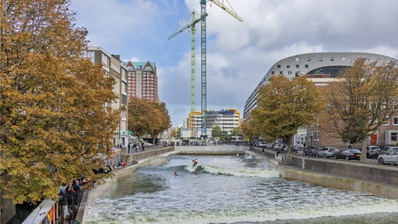 Surfer auf einem Kanal neben der Markthal, Bäume und Kräne