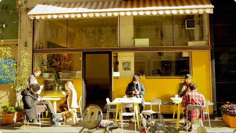 Menschen sitzen vor einem Cafe