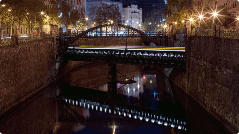 Eine nächtliche Ansicht einer Brücke über einen Kanal in Wien.