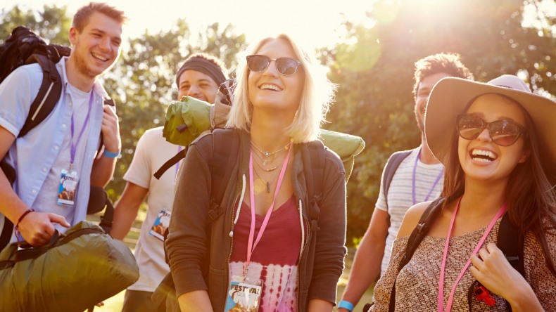 Eine Gruppe junger Menschen mit Reisegepäck und Festivalpass um den Hals.